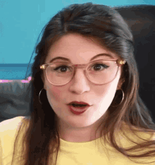 a woman wearing glasses and a yellow shirt is making a surprised face
