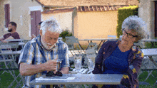 a man and a woman sit at a table looking at a menu