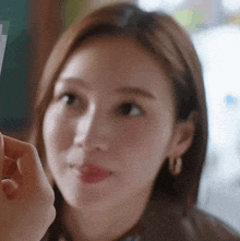 a close up of a woman 's face with a person holding a piece of paper to her face .