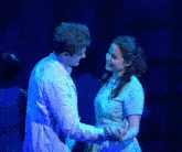 a man and a woman are looking into each other 's eyes on stage