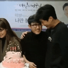 a group of people are standing around a cake with candles .