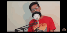 a man in a red california shirt is singing into a microphone