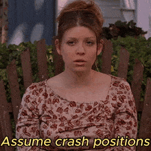 a woman sits in a wooden chair with the words assume crash positions behind her
