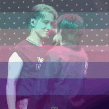 a couple of people standing next to each other with a rainbow flag behind them