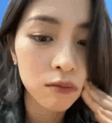 a close up of a woman 's face with a blue sky behind her