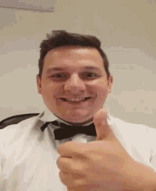 a man wearing a bow tie gives a thumbs up