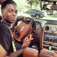 a young man is sitting in a bentley car and giving the middle finger