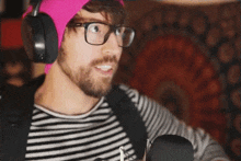 a man wearing headphones and a pink beanie is playing a guitar