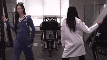 a woman in a white lab coat stands next to a woman in a blue hoodie that says ' nz ' on it