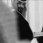 a black and white photo of a man with a beard and a keffiyeh