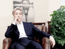 a man in a suit is sitting in a chair with his hand on his chin