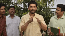 a man with a beard is talking to a group of men while standing in front of trees .