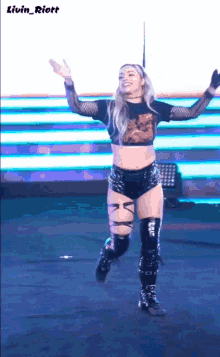 a woman in a crop top and shorts is dancing on a stage with the name livin_riott written above her