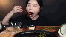 a woman is eating food with chopsticks from a bowl