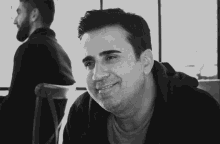 a black and white photo of a man smiling in front of another man