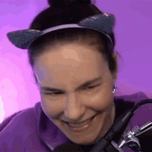 a woman wearing a cat ear headband is smiling and looking at the camera .