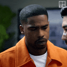 a man in an orange jacket with the letters be on the bottom