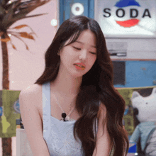 a woman stands in front of a sign that says soda