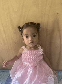 a little girl is wearing a pink dress with pearls