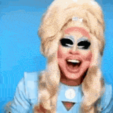 a drag queen wearing a wig and sunglasses is laughing