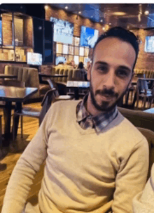 a man with a beard sits in a restaurant
