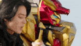 a man eating a banana next to a red and gold robot