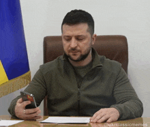 a man sitting at a desk looking at a cell phone with the caption @ukrclassicmemes
