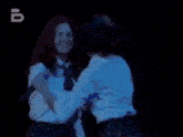 a woman and a child are dancing in a dark room with the letter b on the bottom right
