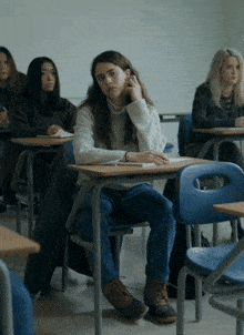 a girl sits at a desk in a classroom