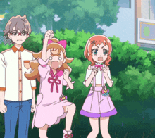 a girl in a pink dress with a bow on her head stands next to a boy and another girl