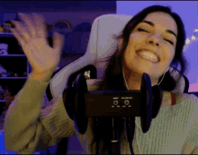 a woman wearing headphones is smiling and waving while sitting in a chair