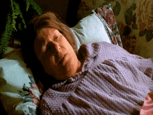 a woman in a purple sweater is sleeping on a bed