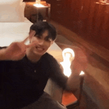 a man giving a peace sign while sitting on a bed
