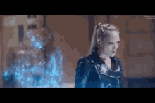a woman in a leather jacket is standing next to a ghost in a room .