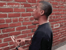 a man standing in front of a brick wall with the hashtag #main-chat-shit on the bottom