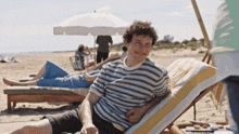 a man in a striped shirt sits in a beach chair