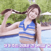 a woman in a braided ponytail stands in front of a pool