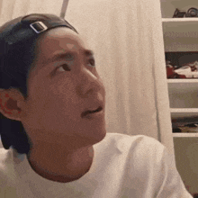 a man wearing a baseball cap and a white shirt looks to the side