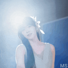 a woman with a flower in her hair is standing in front of a blue background with the letters ms on it