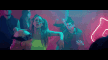 a group of people are dancing in a dark room with neon lights behind them