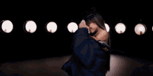 ariana grande is dancing on a stage in a dark room with lights behind her .
