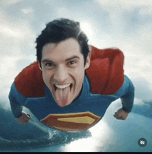 a man in a superman costume is flying through the air with his tongue out