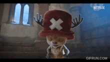 a stuffed animal wearing a red hat with a cross on it