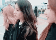 three women are standing next to each other on a sidewalk and talking .