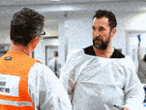 a man wearing a vest that says " safety md " talks to another man
