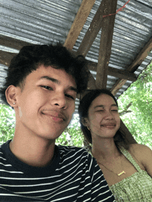 a man and a woman are posing for a picture under a wooden structure