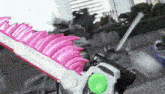 a person is holding a pink and white sword with a green button on the end .