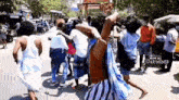 a group of people are dancing on a street in front of a crowd .