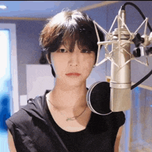 a young man is standing in front of a microphone in a recording studio .