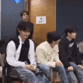 a group of young men are sitting in a room in front of a door .